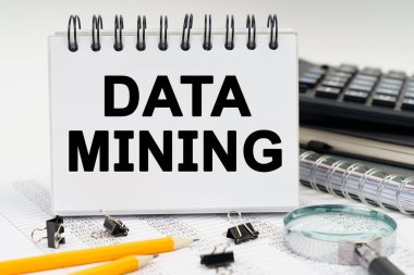 İş ve ekonomi kavramı. Masanın üzerinde bir büyüteç, kalemler, günlükler ve üzerinde DATA MINING yazan bir defter var.