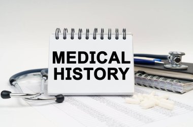 Tıp ve sağlık konsepti. Masanın üzerinde bir stetoskop, bir günlük ve üzerinde tıbbi tarih yazan bir defter var.