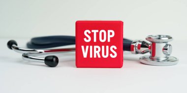 Tıp ve sağlık konsepti. Masanın üzerinde steteskop ve kırmızı bir küp var. Üzerinde DUR VIRUS yazıyor.