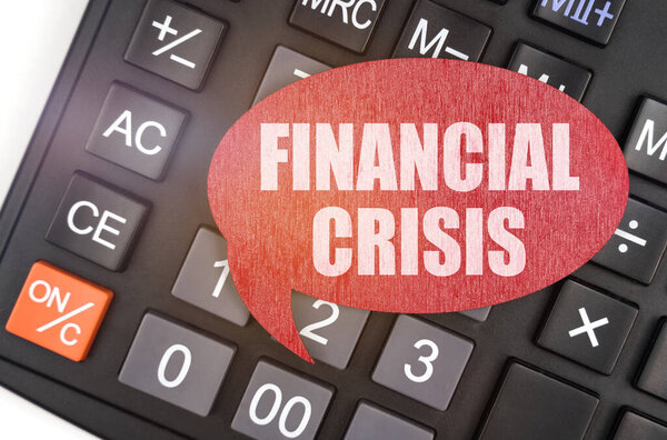Business and finance concept. There is a red plaque on the calculator that says - FINANCIAL CRISIS