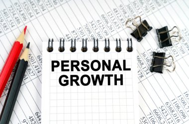 İş konsepti. Masada raporlar, kalemler ve üzerinde kişisel gelişim yazan bir defter var.