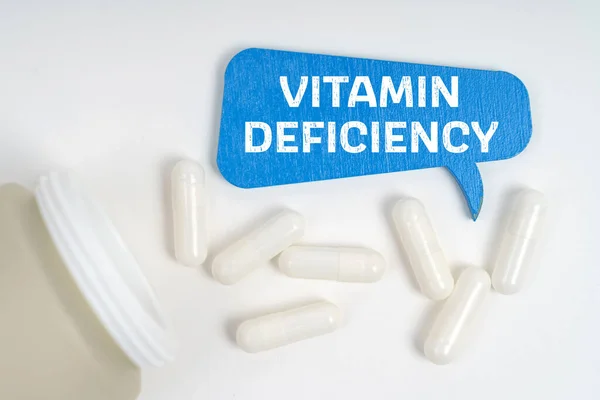 Tıp ve sağlık konsepti. Masanın üzerinde haplar ve vitamin eksikliği yazan mavi bir tabela var.