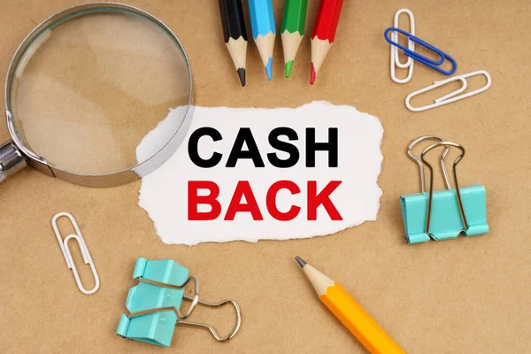 Business concept. On the table are pencils, paper clips, a magnifying glass and paper with the inscription - CASH BACK