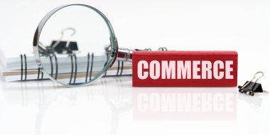 İş konsepti. Masanın üzerinde bir defter, bir büyüteç ve üzerinde COMERCE yazan bir tablet var.