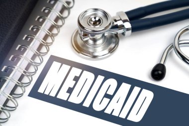 Tıp konsepti. Masanın üzerinde bir steteskop ve bir defter var, yazının yanında - MEDICAID