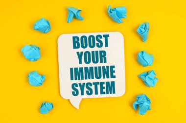 Tıp konsepti. Sarı arka planda, mavi kağıt parçaları ve üzerinde yazı olan bir tabela - Bağışıklık Sisteminizi Destekleyin