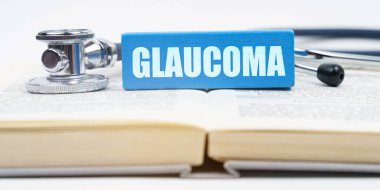 Tıp konsepti. Kitapta bir steteskop ve üzerinde GLAUCOMA yazan bir jenga var.
