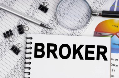 İş ve ekonomi kavramı. Masanın üzerinde bir büyüteç, raporlar, bir kalem ve yazılı bir defter var.