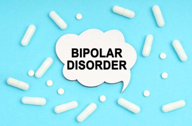 Medicine concept. On a blue background pills and a plate. Inside the sign it says - BIPOLAR DISORDER