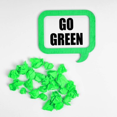Ecology concept. On a white background, green crumpled pieces of paper and a sign inside which the inscription - Go Green
