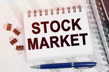 İş konsepti. Masanın üzerinde bir kalem ve üzerinde yazılar olan bir defter var - STOCK MARKET