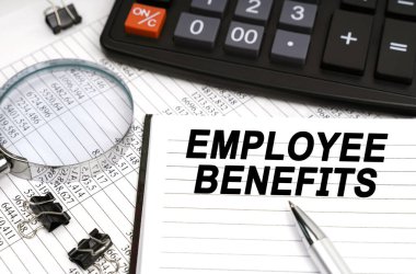 İş konsepti. Masanın üzerinde bir büyüteç, bir hesap makinesi, bir kalem ve üzerinde yazılar olan bir defter var.