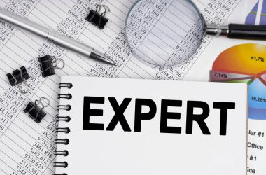 İş ve ekonomi kavramı. Masanın üzerinde bir büyüteç, raporlar, bir kalem ve üzerinde yazı olan bir defter var.