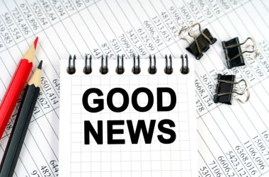 Ekonomi ve iş kavramı. Masanın üzerinde raporlar, kalemler ve üzerinde iyi haberler yazan bir defter var.