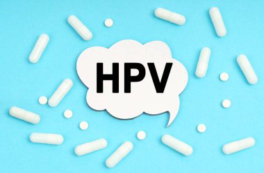 Tıp konsepti. Mavi arka plan hapları ve bir tabakta. Tabelanın içinde HPV yazıyor.