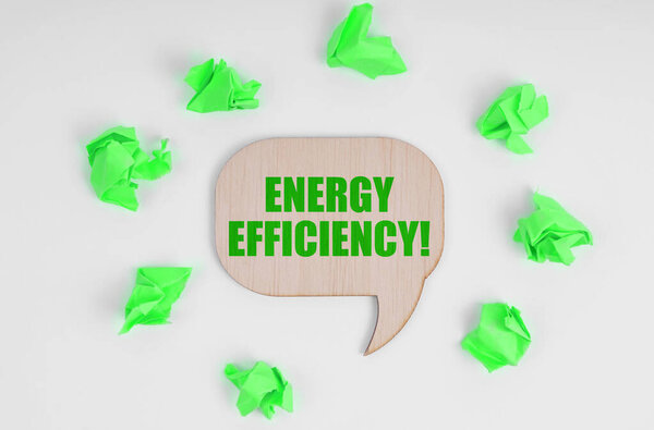 Ecology concept. On a white background, there are crumpled green pieces of paper and a wooden sign with the inscription - Energy Efficiency