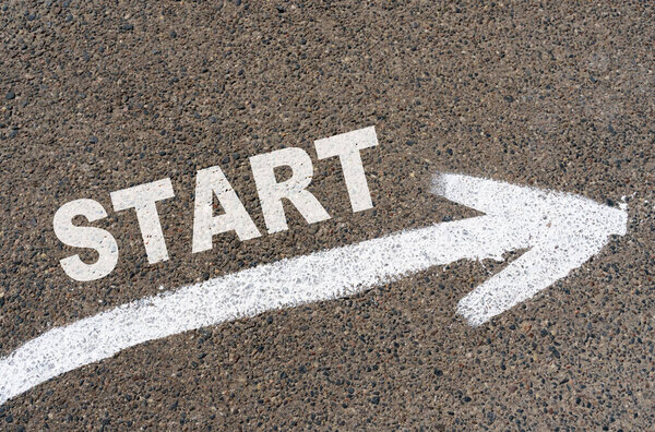 Бизнес-концепция. На асфальтовых дорожных разметках стрелка с надписью - START