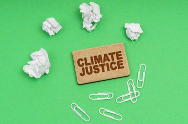 Ekoloji konsepti. Yeşil bir arkaplanda, buruşmuş kağıt, ataç ve yazılı bir tabela - İklim adaleti