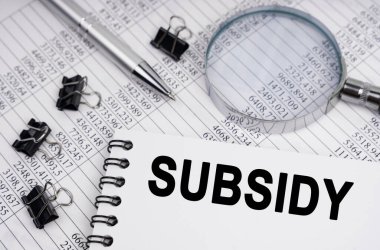 İş ve ekonomi kavramı. Masanın üzerinde bir büyüteç, raporlar, bir kalem ve üzerinde yazı olan bir defter var. -