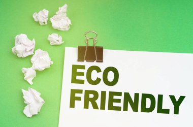 Ekoloji konsepti. Yeşil bir arka planda, buruşmuş kağıt ve yazılı bir çarşaf - çevre dostu