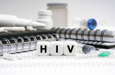 Tıp konsepti. Masanın üzerinde günlükler, ilaçlar ve üzerinde HIV yazan küpler var.