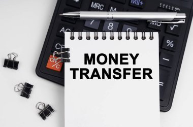 İş ve ekonomi kavramı. Masanın üzerinde bir hesap makinesi, bir kalem ve üzerinde para transferinin yazılı olduğu bir defter var.