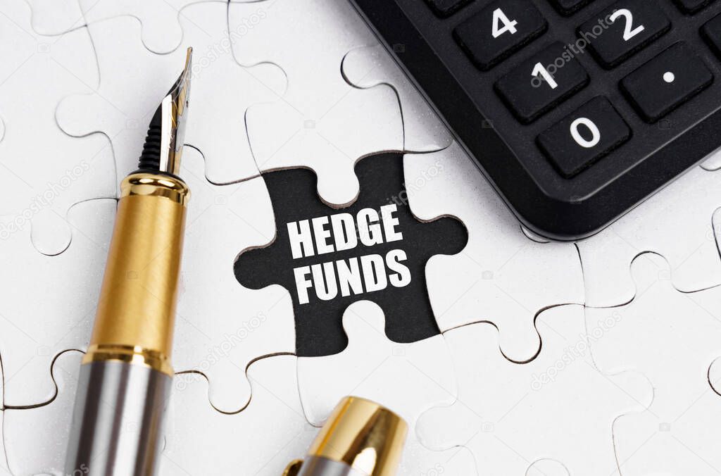 Business and finance concept. On white puzzles there is a calculator and a pen, in an open cell there is an inscription - HEDGE FUNDS