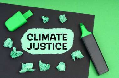 Ekoloji konsepti. Yeşil bir arka planda, bir işaret, siyah bir sayfa ve üzerinde iklim adaleti yazan yırtık bir kağıt.