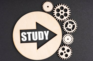 İş ve finans kavramı. Siyah bir arkaplanda, ahşap dişliler ve içinde bir çember var. Üzerinde yazılar olan bir ok var.