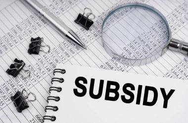 İş ve ekonomi kavramı. Masanın üzerinde bir büyüteç, raporlar, bir kalem ve bir defter var.