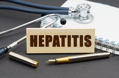 Tıp konsepti. Masanın üzerinde bir defter, bir stetoskop ve üzerinde HEPATITIS yazan bir tabela var.