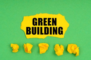 Ekoloji konsepti. Yeşil arka planda, buruşmuş sarı kağıt ve üzerinde yeşil bina yazan bir çarşaf.