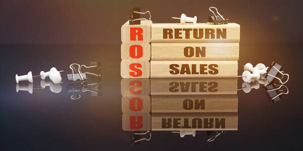 Концепция бизнеса и права. На черной отражающей поверхности лежат кнопки и деревянные доски с надписью - Return On Sales