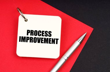 Endüstri ve iş konsepti. Siyah ve kırmızı arkaplanda bir kalem ve bir defter bulunur - PROCESS İMPROVEMENT