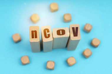 Tıp konsepti. Mavi arkaplanda, tahta küpler ve üzerinde NCOV yazan Jenga.