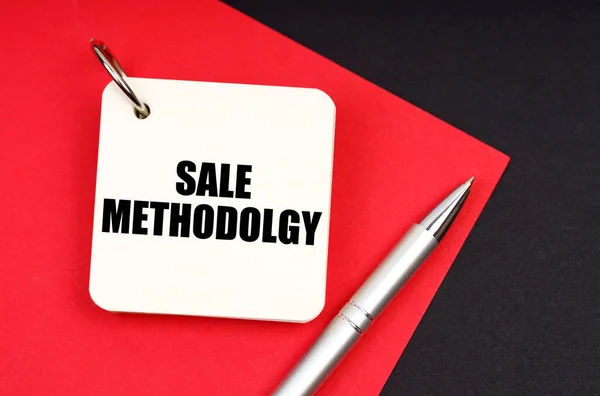 工业和商业概念 在黑色和红色的背景上 有一支笔和一个笔记本 上面有题词 Sale Methodologies Odolgy — 图库照片
