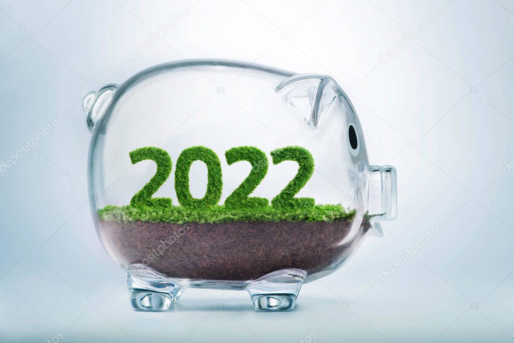 2022 is a good year for business. Grass growing in the shape of year 2022, inside a transparent piggy bank.