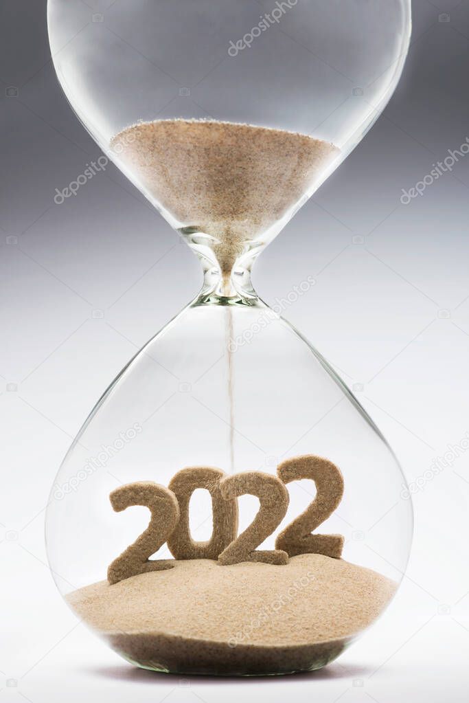 New Year 2022 concept with hourglass falling sand taking the shape of a 2022