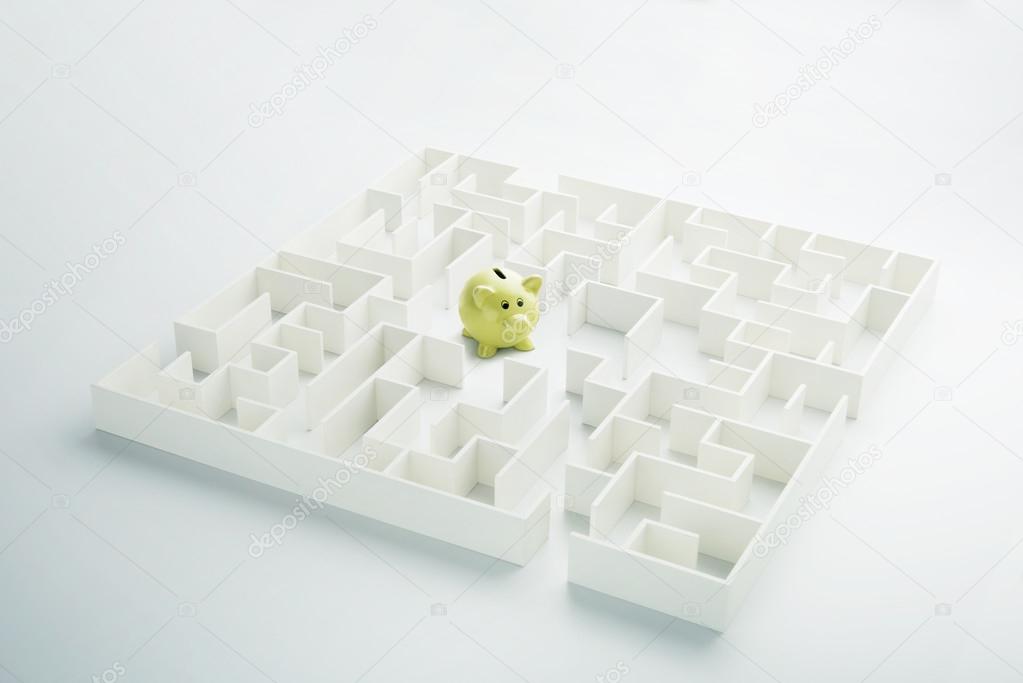 The uncertainty of money and business. Piggy bank hidden inside a maze