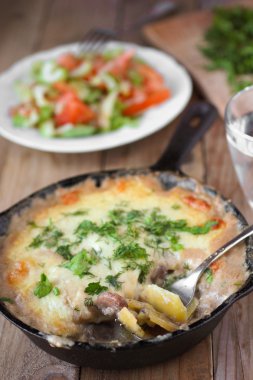 bir tavada mantar ve ahşap masa üzerinde taze otlar patates graten