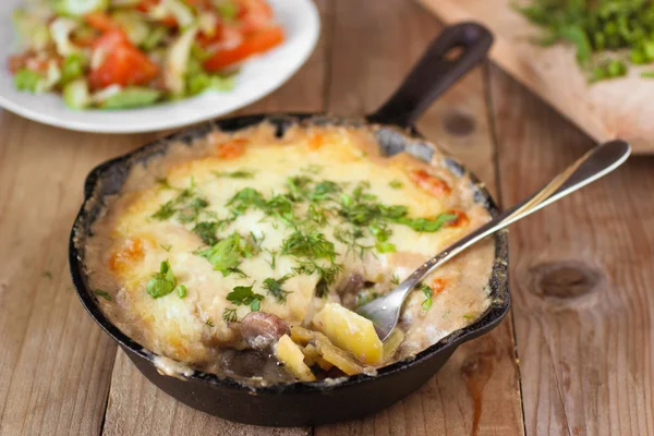 Potato gratin in a pan with mushrooms and fresh herbs on wooden table — Stock Photo, Image