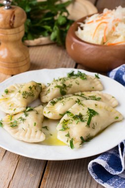 Slav mutfağının geleneksel çanak. Ahşap masa üzerinde beyaz bir tabak patates dolu varenyky