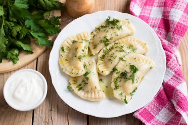 Slav mutfağının geleneksel çanak. Ahşap masa üzerinde beyaz bir tabak patates dolu varenyky