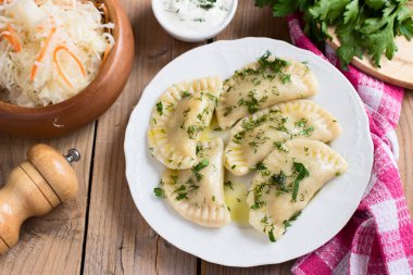 Slav mutfağının geleneksel çanak. Ahşap masa üzerinde beyaz bir tabak patates dolu varenyky