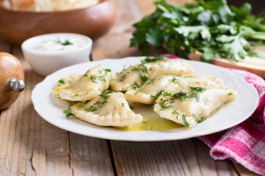 Slav mutfağının geleneksel çanak. Ahşap masa üzerinde beyaz bir tabak patates dolu varenyky