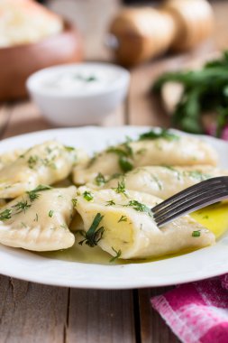 Slav mutfağının geleneksel çanak. Ahşap masa üzerinde beyaz bir tabak patates dolu varenyky