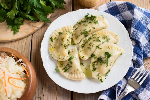 Plat traditionnel de la cuisine slave. Varenyky rempli de pommes de terre sur une assiette blanche sur une table en bois — Photo