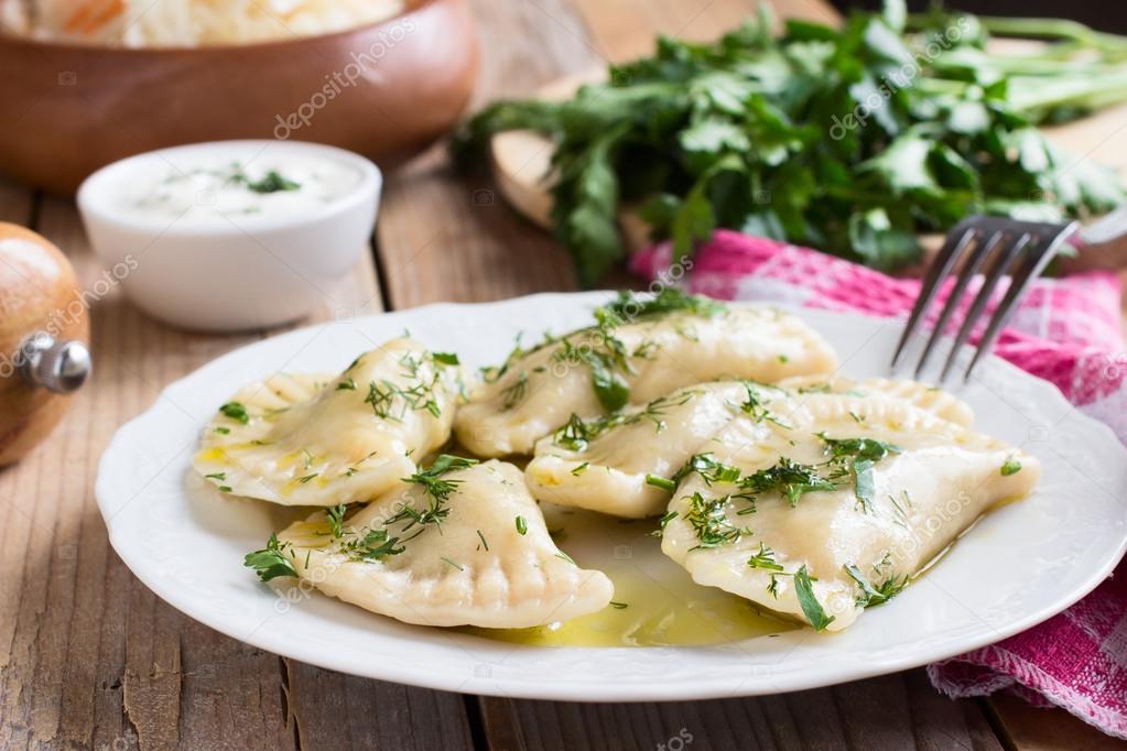 Traditional dish of Slavic cuisine. Potato-filled varenyky on a white plate on wooden table