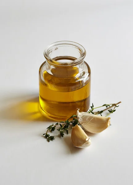 A jar of oil, two garlic cloves and a savory twig — Stock Photo, Image