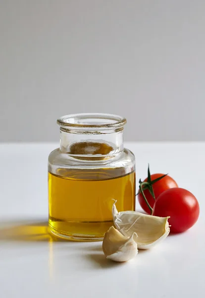 A jar of oil, two garlic cloves and tomatoes — Stock Photo, Image